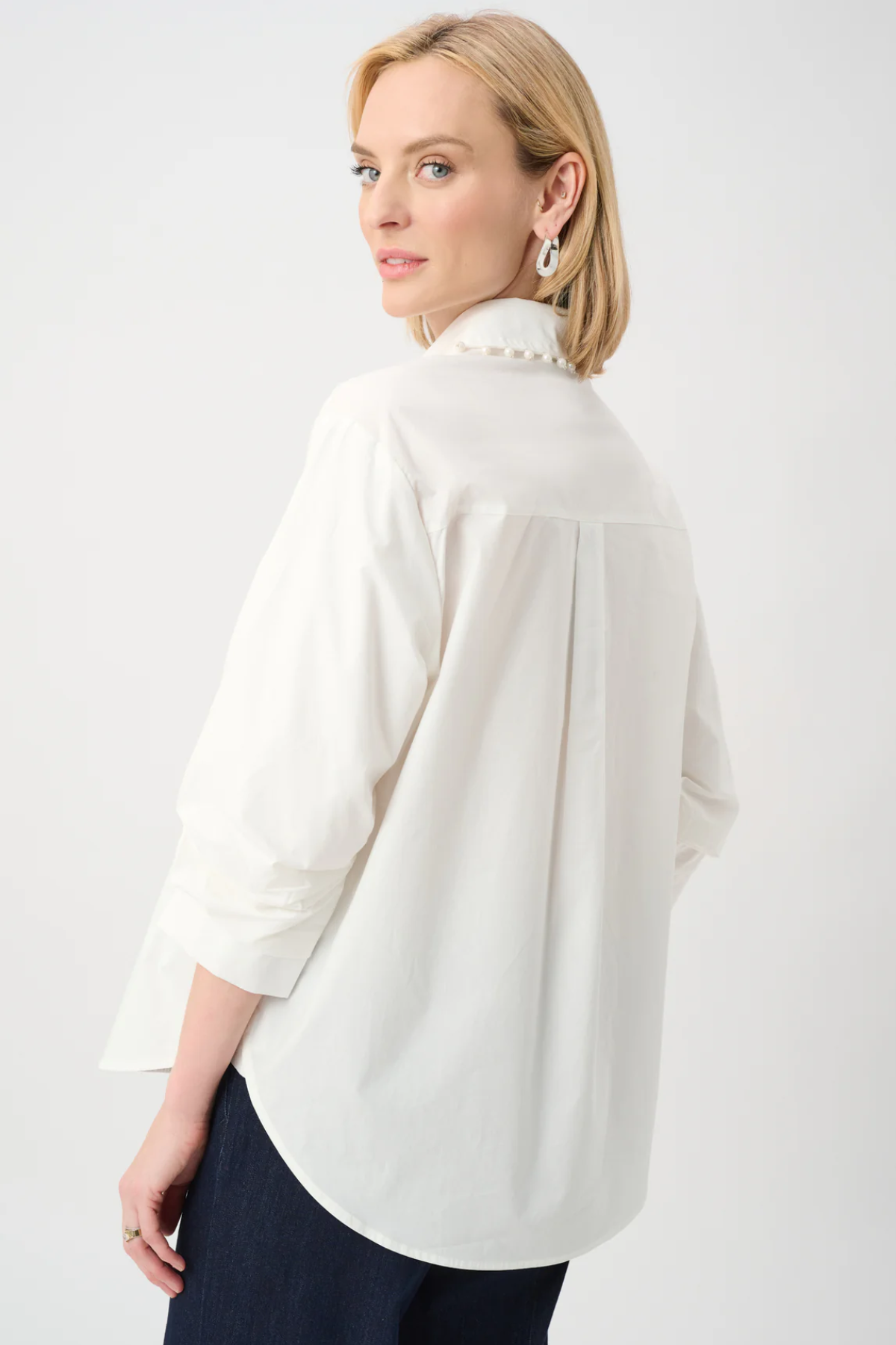 Woman wearing a white blouse with a high collar on a plain background