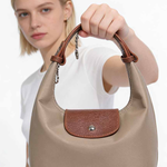 Woman holding a beige handbag with brown accents against a white background
