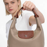 Woman holding a beige handbag with brown accents against a white background