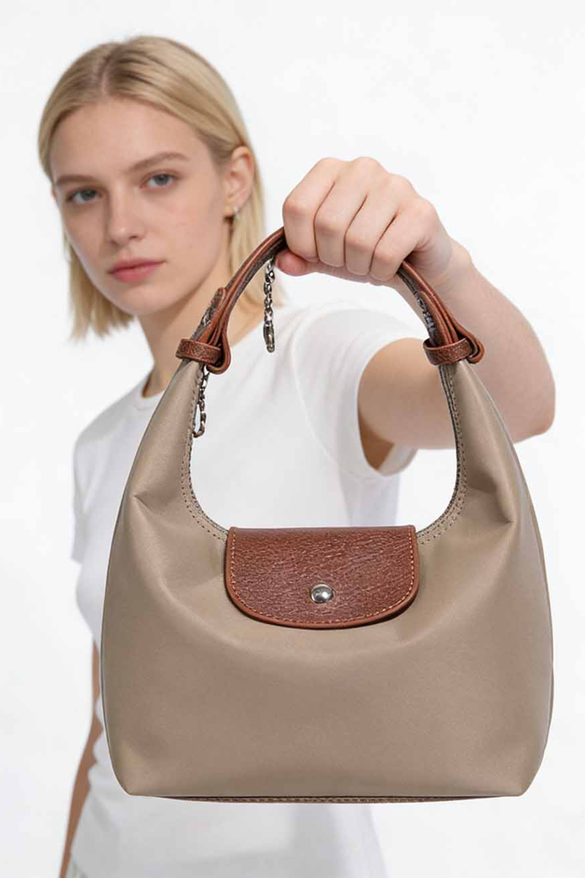 Woman holding a beige handbag with brown accents against a white background