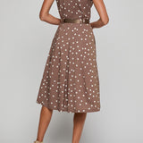 Woman wearing a brown polka dot dress on a gray background
