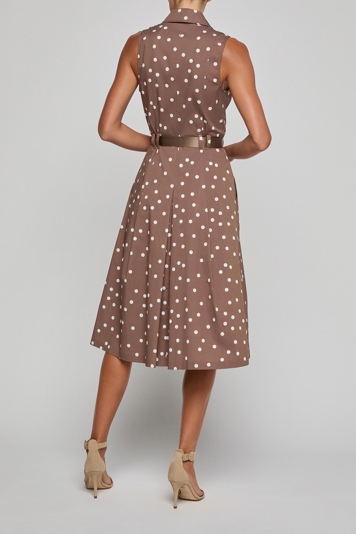 Woman wearing a brown polka dot dress on a gray background
