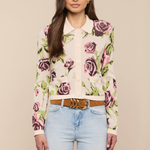 Woman wearing a floral blouse and light blue jeans against a beige background