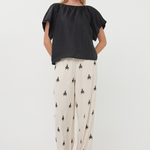 Woman wearing a black top and patterned pants on a white background