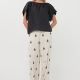 Woman wearing a black top and patterned pants on a white background