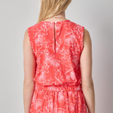 Woman wearing a red floral dress against a plain background
