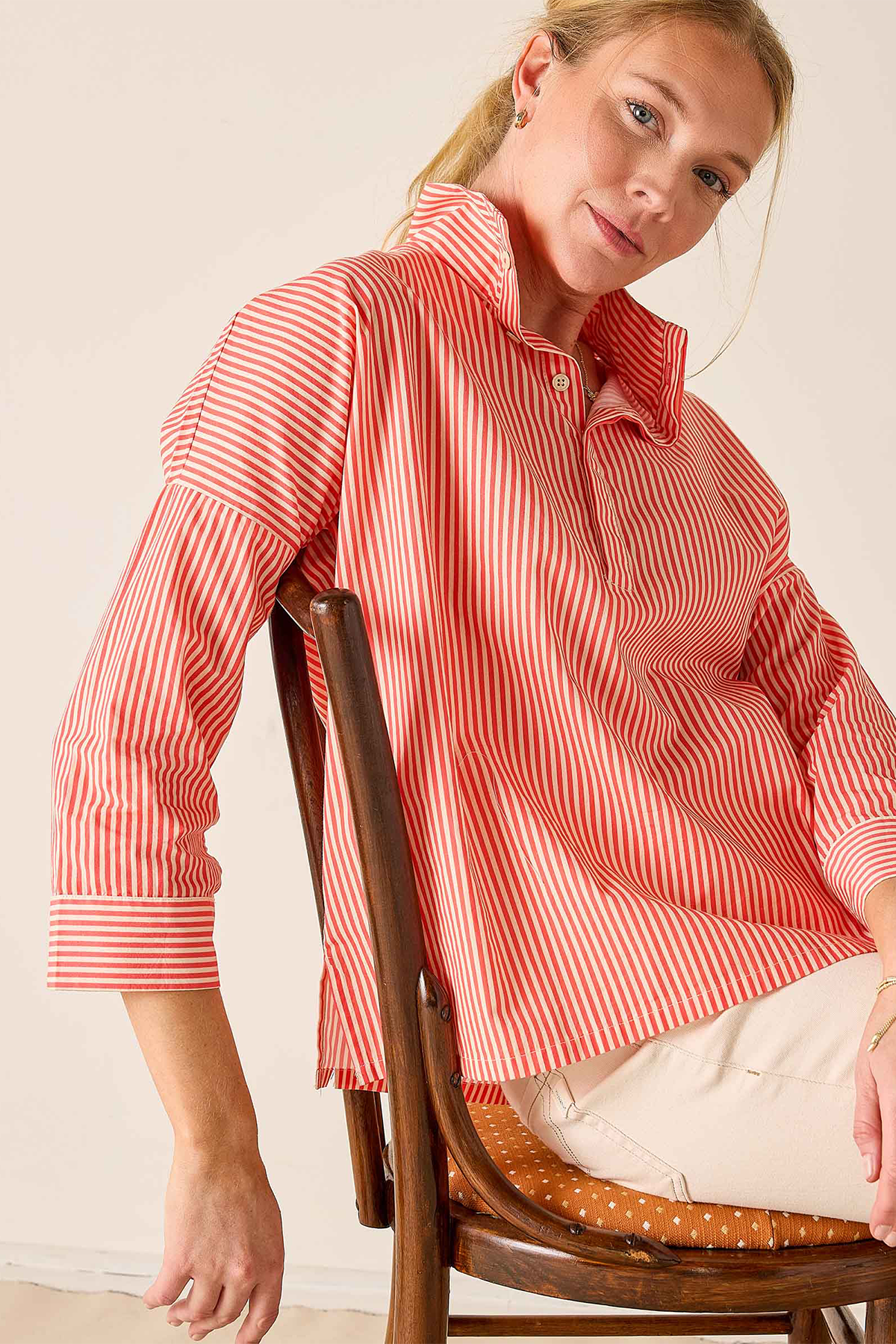 woman in striped button down sitting in chair 