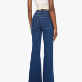 A model shown from the back wearing dark blue high-waisted flare jeans and a cream-colored wrap top, set against a plain white studio background.