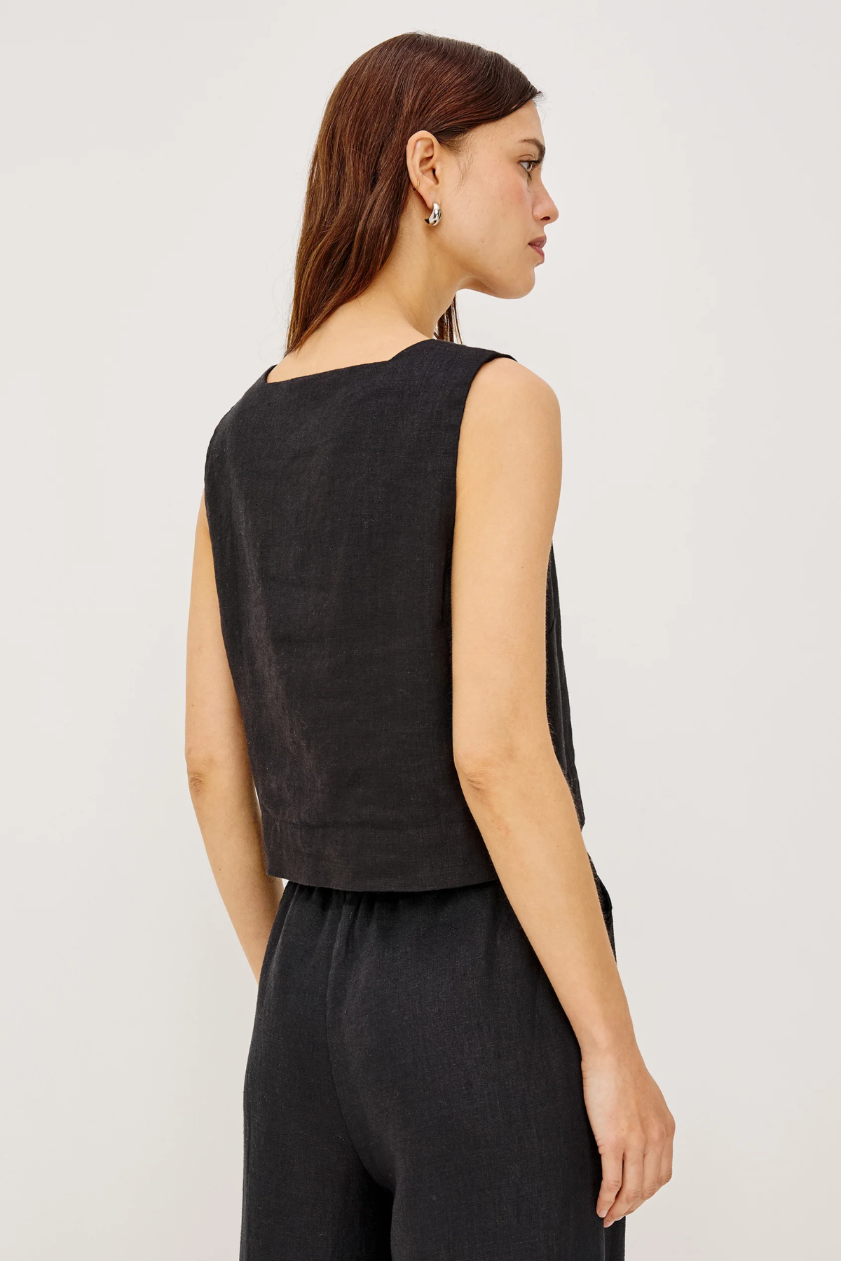 Woman wearing a black sleeveless top and pants against a white background