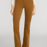 A model wearing a pair of brown corduroy flare pants with a cream knit top and black pointed-toe heels, shown from the chest down against a light gray studio background.