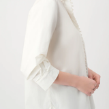 White blouse with ruffled sleeves worn by a person on a white background