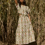 Woman in a floral dress standing in front of a natural background