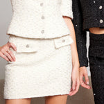 White tweed suit with black pants on a neutral background