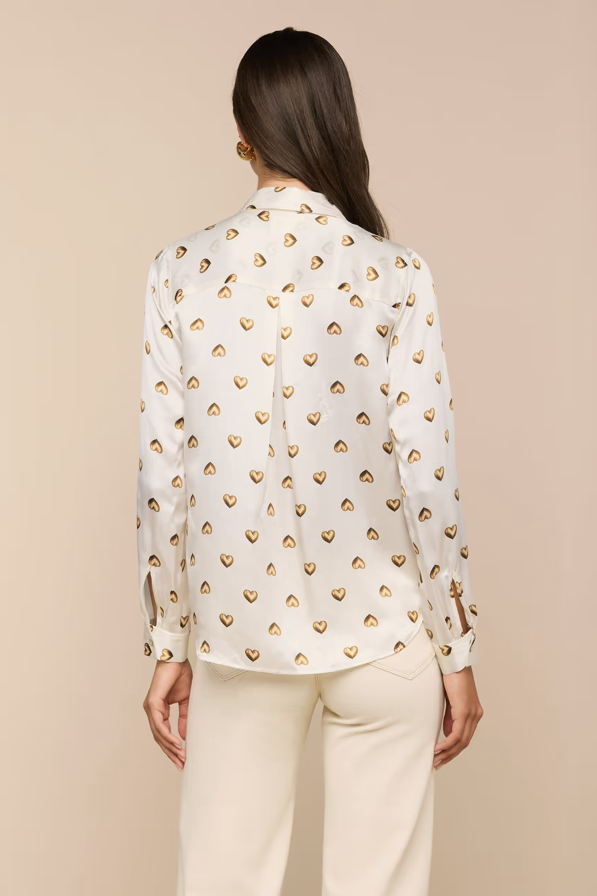 Woman wearing a white blouse with gold heart patterns on a beige background