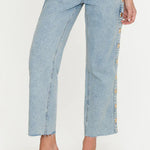 Light blue jeans with floral side panels worn by a person on a white background