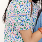 Woman wearing a colorful floral blouse with a white background