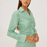 Woman wearing a green and white striped shirt with gold buttons on a white background