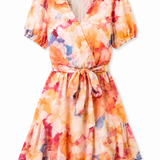 A short-sleeve wrap dress with a tie waist, featuring a vibrant watercolor floral print in orange, pink, yellow, and blue on a white background.