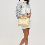 Woman holding a yellow woven handbag against a white background