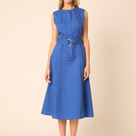 woman in blue belted dress on tan background 