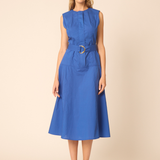 woman in blue belted dress on tan background 