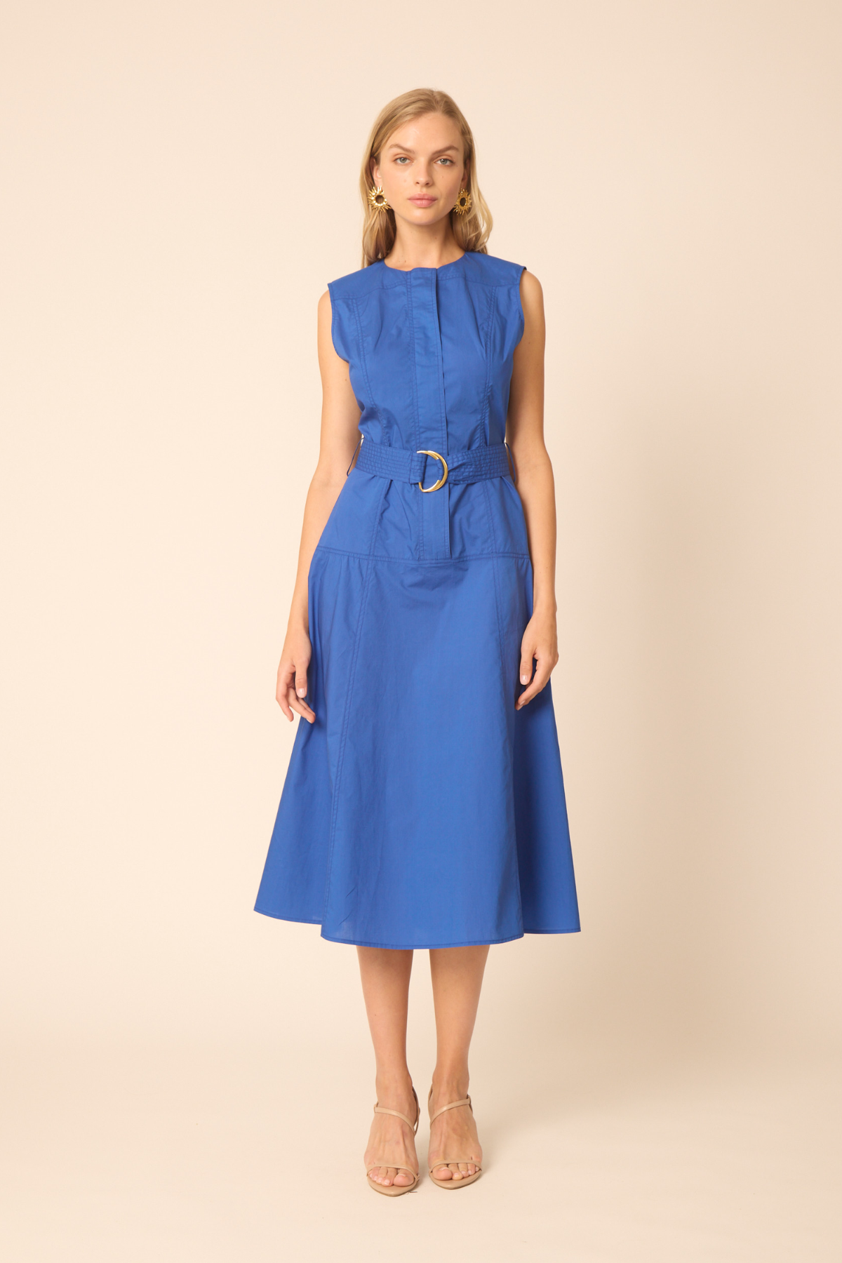 woman in blue belted dress on tan background 