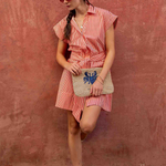 woman in striped mini dress on a brick wall outside 