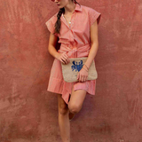 woman in striped mini dress on a brick wall outside 