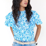 Woman wearing a blue floral top and jeans against a white background