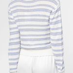 Person wearing a white and blue striped sweater with white pants on a light background