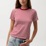Woman wearing a red and white striped shirt with blue jeans on a plain background