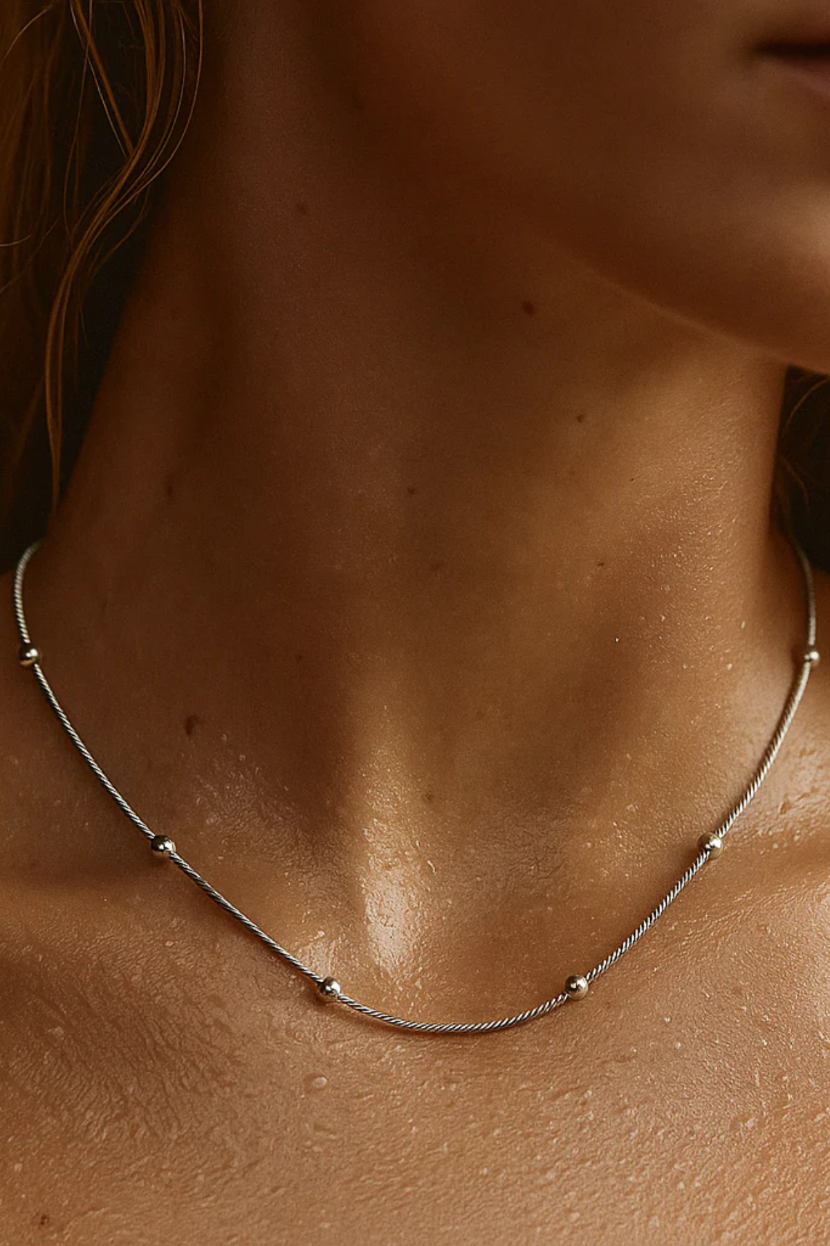 Close-up of a necklace on a person's neck with a neutral background