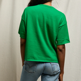 Person wearing a green t-shirt and blue jeans against a plain background
