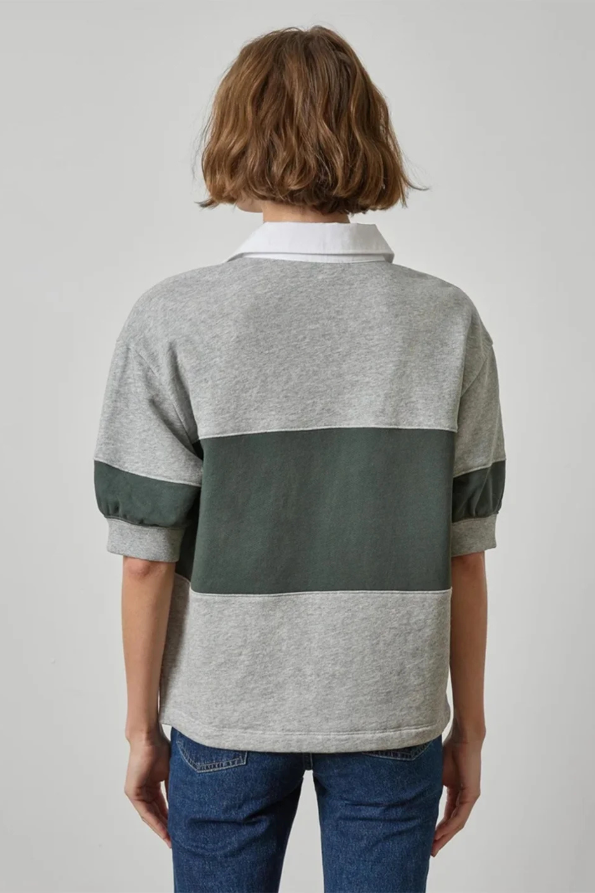 Person wearing a gray and green striped shirt with a plain background