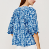 back of woman in blue printed blouse on white background 