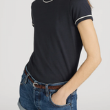 Person wearing a black t-shirt with white trim and denim shorts on a plain background