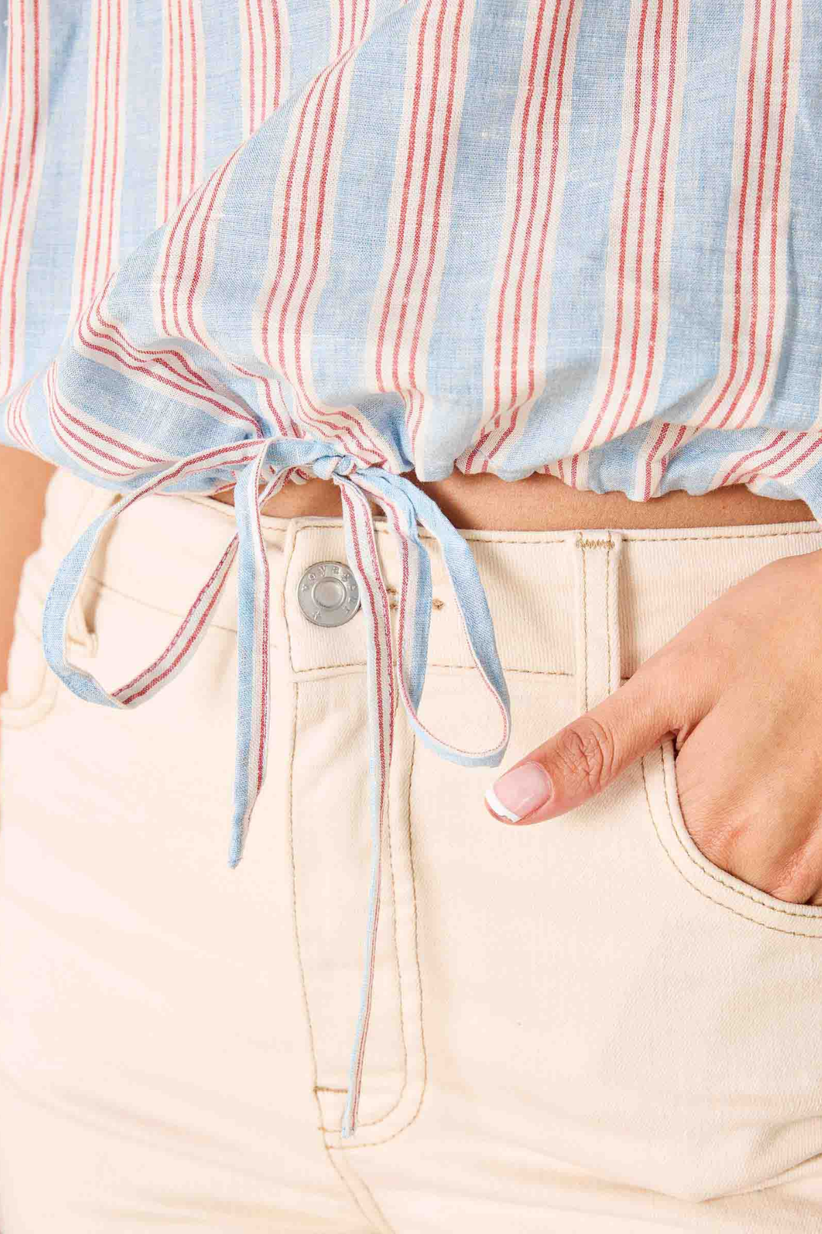 Close-up of a person wearing a striped shirt with a tie and light-colored pants.