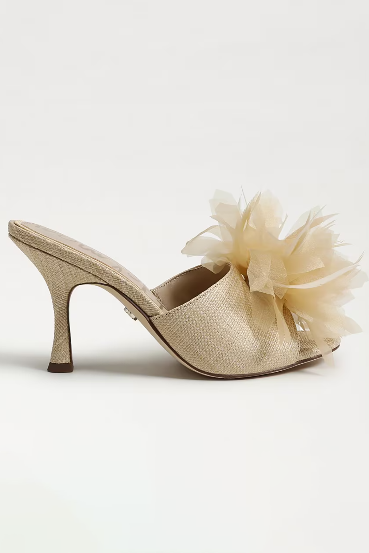 Gold high-heeled shoe with a decorative flower on a white background