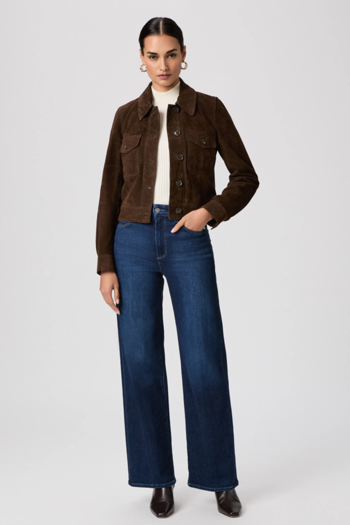 Woman wearing a brown jacket and blue jeans on a white background