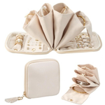 A cream-colored jewelry organizer set shown open and closed, featuring multiple roll-up compartments, ring slots, and small pockets, with gold-tone zipper and ring holder details.