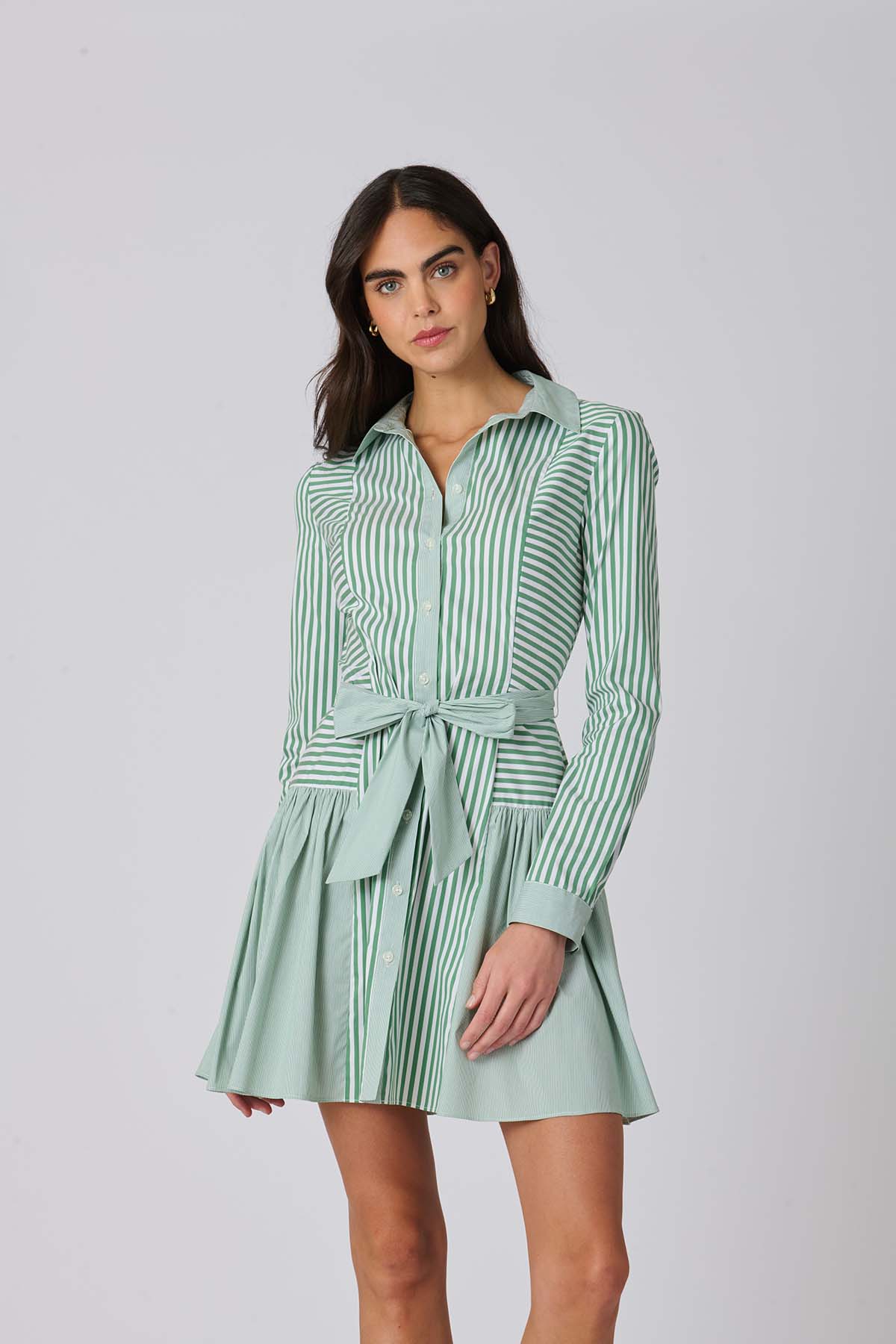 Woman wearing a green and white striped dress against a plain background