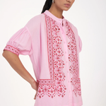 Woman wearing a pink embroidered traditional outfit on a white background