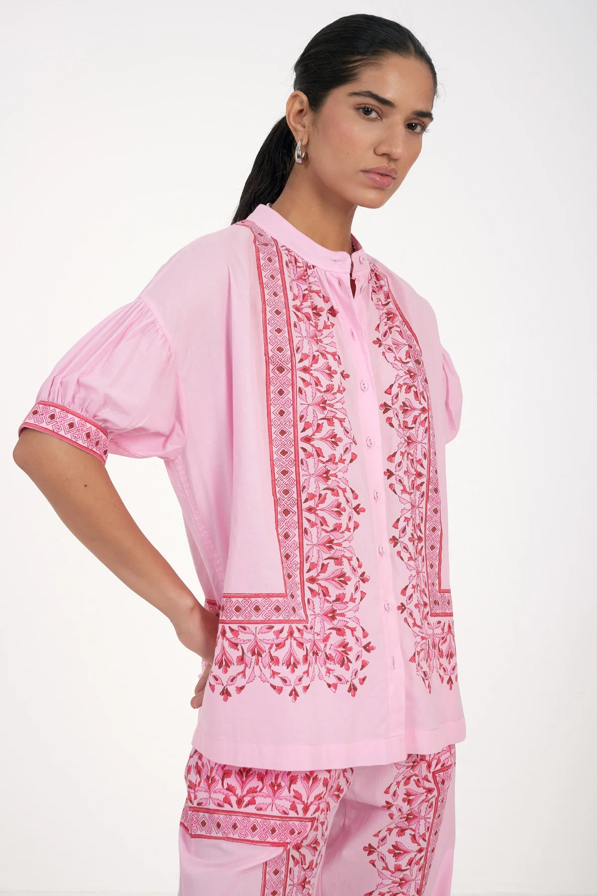 Woman wearing a pink embroidered traditional outfit on a white background