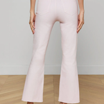 Light pink flared pants worn by a person on a wooden floor with a neutral background