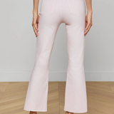 Light pink flared pants worn by a person on a wooden floor with a neutral background