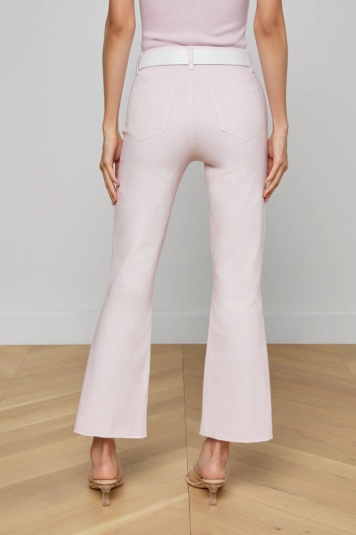 Light pink flared pants worn by a person on a wooden floor with a neutral background