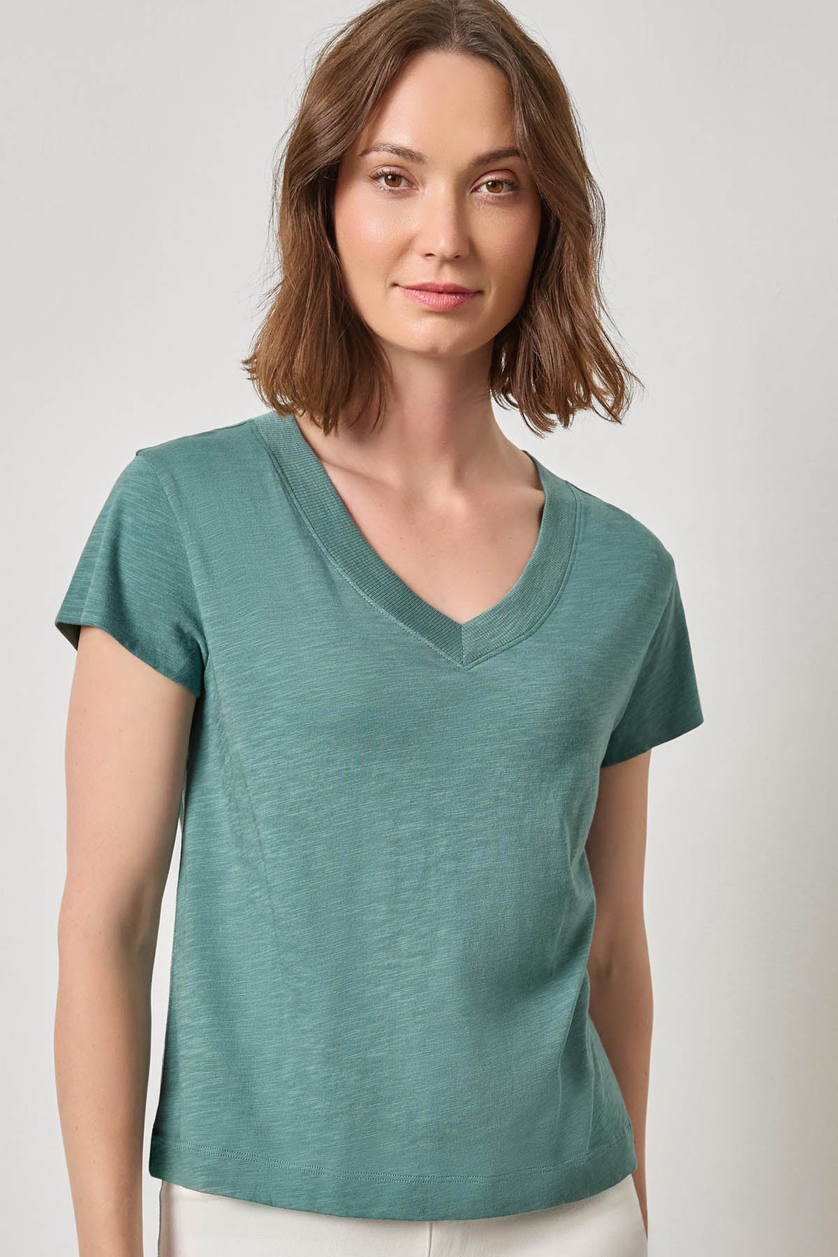 Woman wearing a teal V-neck t-shirt against a plain background