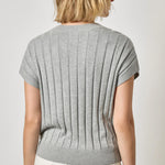 Person wearing a gray ribbed knit top against a white background