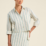Woman wearing a striped dress with rolled-up sleeves on a beige background