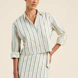 Woman wearing a striped dress with rolled-up sleeves on a beige background
